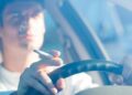 Conductor fumando un cigarrillo al volante, posible multa DGT por distracción y colillas