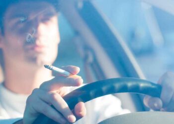 Conductor fumando un cigarrillo al volante, posible multa DGT por distracción y colillas