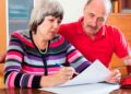 Pareja senior revisa documentos para calcular la pensión contributiva con 30 años cotizados y edad de jubilación de 66 años y 8 meses