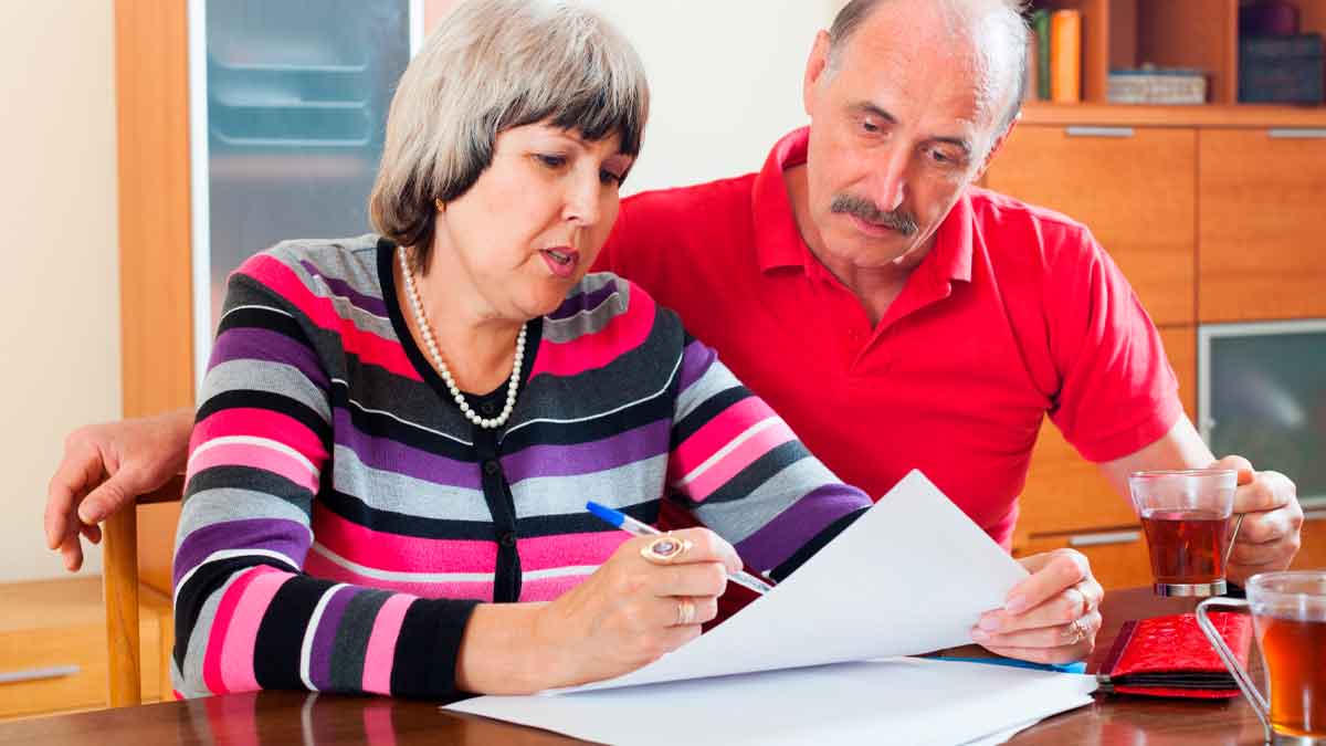 Pareja senior revisa documentos para calcular la pensión contributiva con 30 años cotizados y edad de jubilación de 66 años y 8 meses