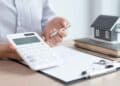 Persona calculando hipoteca con IRPH sobre documentos y maqueta de casa