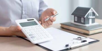 Persona calculando hipoteca con IRPH sobre documentos y maqueta de casa