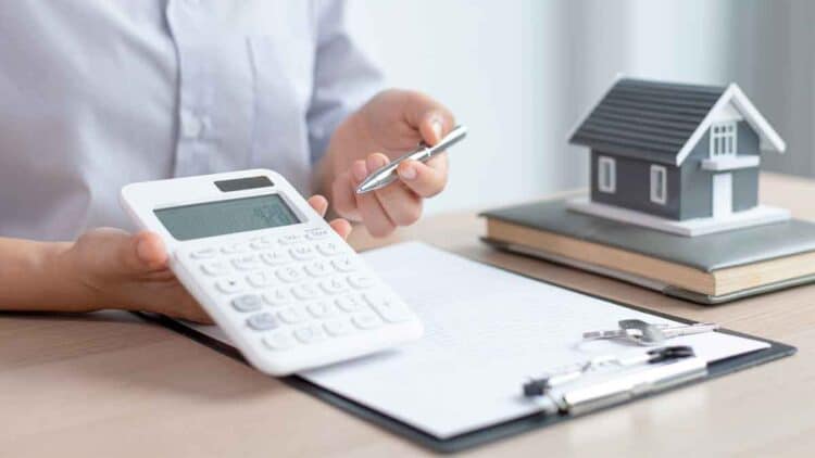 Persona calculando hipoteca con IRPH sobre documentos y maqueta de casa