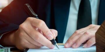 Mano de empresario firmando documento de reclamación de consumo