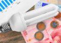 Bombilla de bajo consumo sobre billetes y monedas de euro, símbolo del ahorro del 65 % con el Bono Social Eléctrico en Andalucía 2025