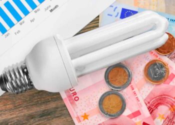 Bombilla de bajo consumo sobre billetes y monedas de euro, símbolo del ahorro del 65 % con el Bono Social Eléctrico en Andalucía 2025