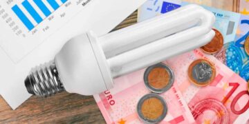 Bombilla de bajo consumo sobre billetes y monedas de euro, símbolo del ahorro del 65 % con el Bono Social Eléctrico en Andalucía 2025