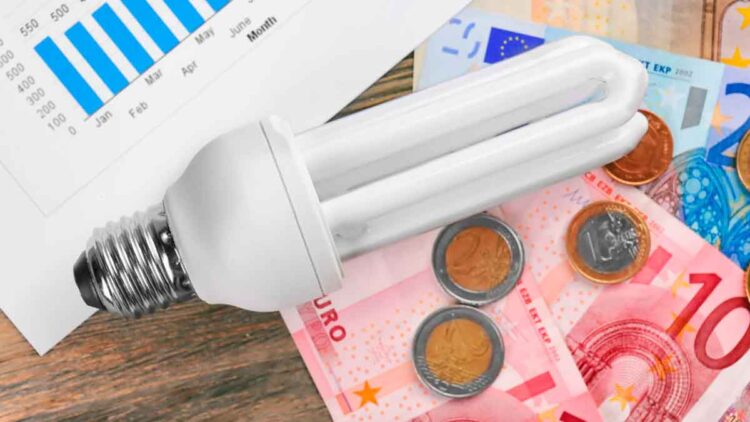 Bombilla de bajo consumo sobre billetes y monedas de euro, símbolo del ahorro del 65 % con el Bono Social Eléctrico en Andalucía 2025
