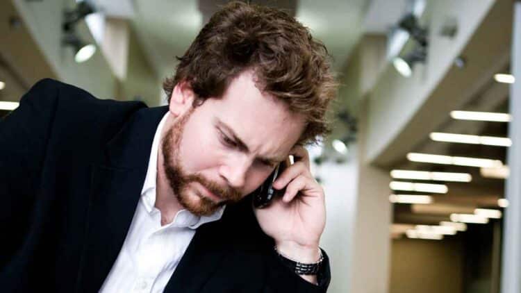 Hombre preocupado habla por teléfono, posible víctima de una estafa de clonación de voz y suplantación de identidad.