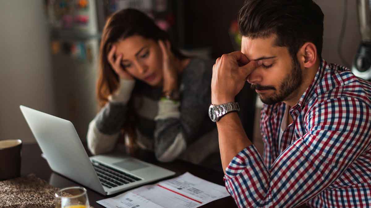 Pareja joven preocupada revisa facturas y portátil mientras busca 3 vías legales para evitar embargos y sanciones de Hacienda