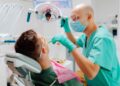 Dentista atendiendo a un paciente durante un tratamiento bucodental, gasto médico que puede desgravar en la Renta 2024/25 en algunas comunidades