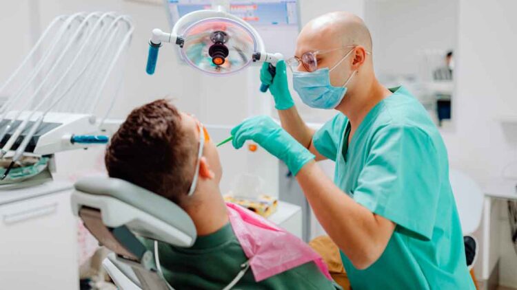 Dentista atendiendo a un paciente durante un tratamiento bucodental, gasto médico que puede desgravar en la Renta 2024/25 en algunas comunidades