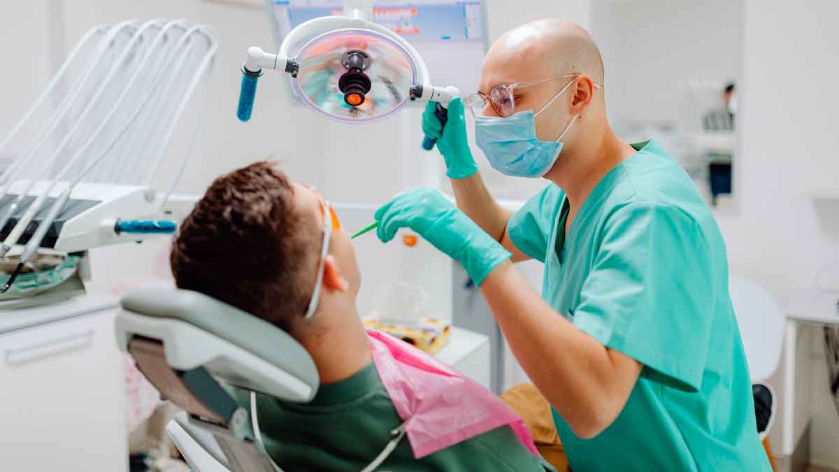 Dentista atendiendo a un paciente durante un tratamiento bucodental, gasto médico que puede desgravar en la Renta 2024/25 en algunas comunidades