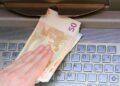 Mano retirando billetes de 50 euros en un cajero automático, acción que Hacienda puede sancionar con hasta 150 000 euros