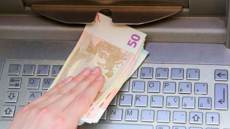 Mano retirando billetes de 50 euros en un cajero automático, acción que Hacienda puede sancionar con hasta 150 000 euros