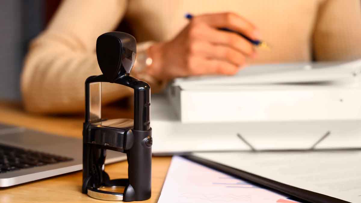 Sello notarial sobre escritorio, documentos y heredera firmando para desbloquear una herencia bloqueada