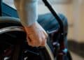 Mano de una persona en silla de ruedas simboliza la pensión de incapacidad permanente y el límite de edad fijado por el INSS