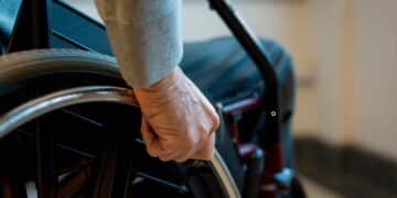 Mano de una persona en silla de ruedas simboliza la pensión de incapacidad permanente y el límite de edad fijado por el INSS