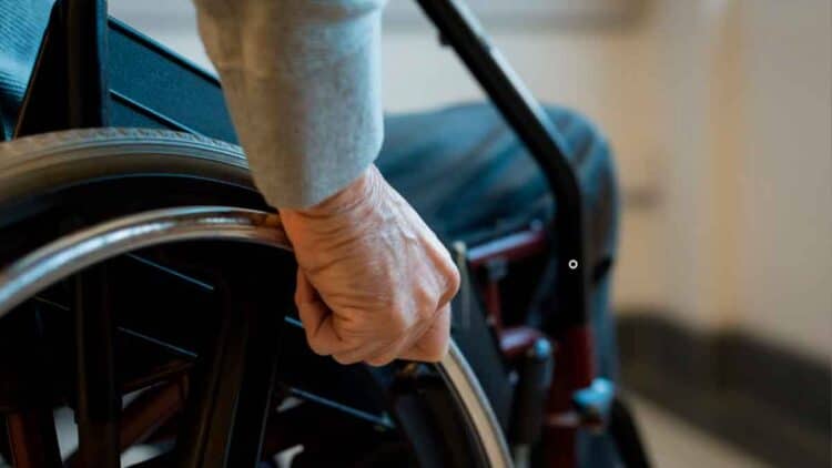 Mano de una persona en silla de ruedas simboliza la pensión de incapacidad permanente y el límite de edad fijado por el INSS