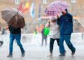 Personas con paraguas caminando bajo la lluvia en Andalucía durante el aviso amarillo decretado por la AEMET