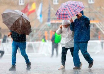 Personas con paraguas caminando bajo la lluvia en Andalucía durante el aviso amarillo decretado por la AEMET