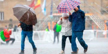 Personas con paraguas caminando bajo la lluvia en Andalucía durante el aviso amarillo decretado por la AEMET