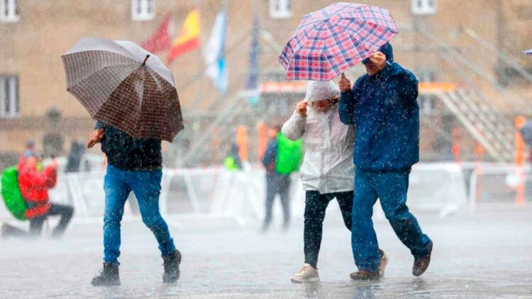 Personas con paraguas caminando bajo la lluvia en Andalucía durante el aviso amarillo decretado por la AEMET