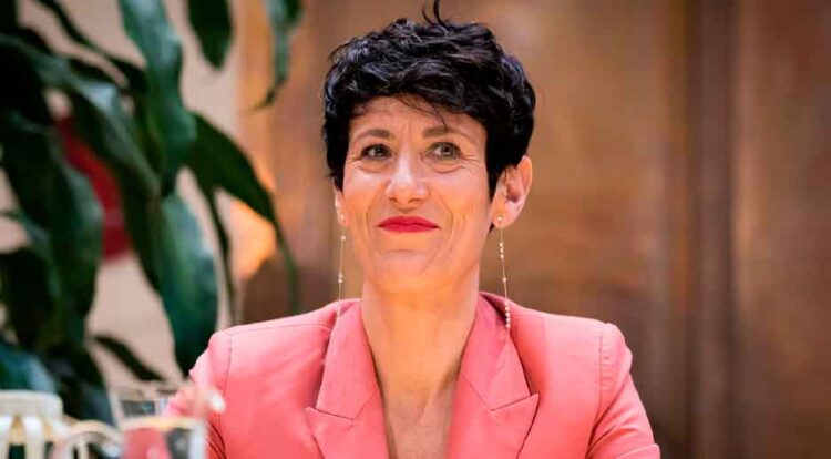 Mujer sonriente con blazer rosa que representa a las madres que pueden sumar hasta 5 años de cotización por maternidad