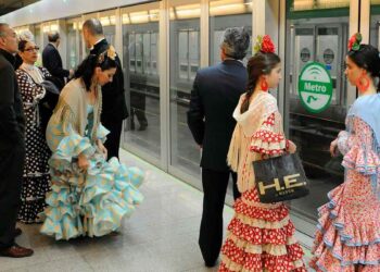 Pasajeros con trajes de flamenca esperan el Metro de Sevilla en el servicio especial hacia la Feria 2025