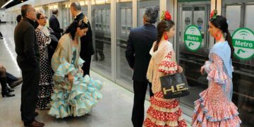 Pasajeros con trajes de flamenca esperan el Metro de Sevilla en el servicio especial hacia la Feria 2025