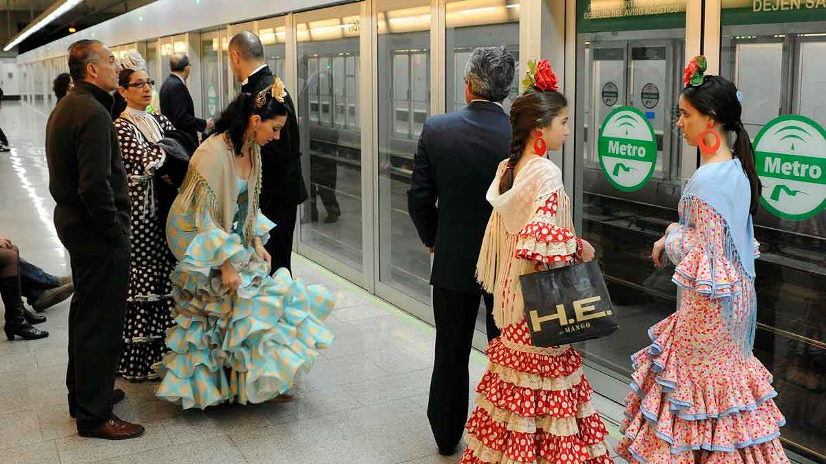 Pasajeros con trajes de flamenca esperan el Metro de Sevilla en el servicio especial hacia la Feria 2025