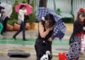Mujeres con traje de flamenca sujetan paraguas volteados por viento y lluvia durante chubascos en Andalucía (7-5-2025)