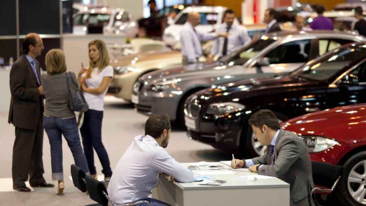Personas comparando precios y modelos en concesionario de coches nuevos en 2025