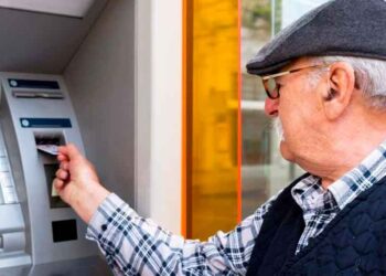 Pensionista sacando dinero en un cajero automático tras recibir la paga extra de verano de la Seguridad Social