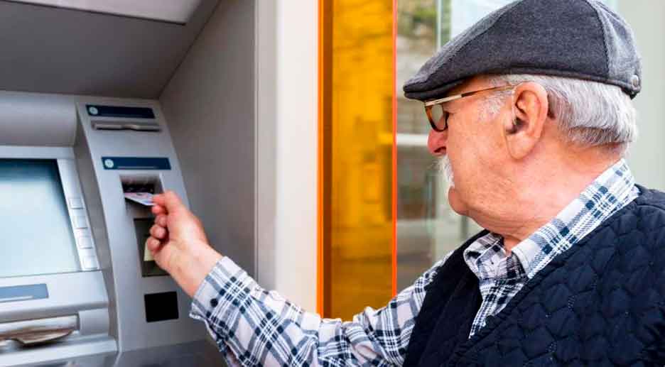 Pensionista sacando dinero en un cajero automático tras recibir la paga extra de verano de la Seguridad Social
