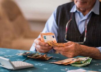 Pensionista contando billetes de euro tras recibir la paga extra de verano 2025 con subida incluida