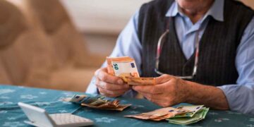 Pensionista contando billetes de euro tras recibir la paga extra de verano 2025 con subida incluida