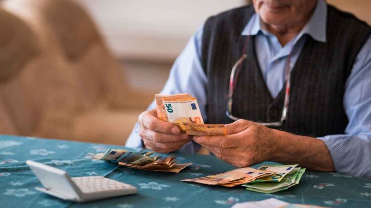 Pensionista contando billetes de euro tras recibir la paga extra de verano 2025 con subida incluida