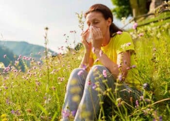 Mujer con alergia en primavera sentada en un campo lleno de flores y polen