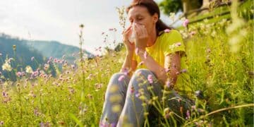 Mujer con alergia en primavera sentada en un campo lleno de flores y polen