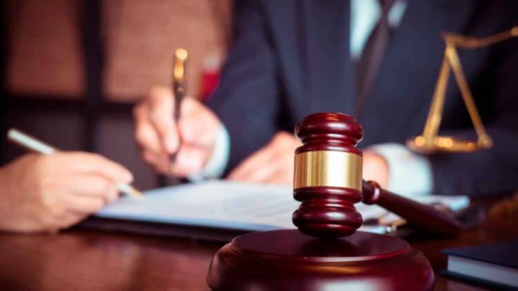 Mazo del juez sobre una mesa mientras un letrado firma la sentencia que otorga incapacidad absoluta y pensión de 2.000 € a una profesora