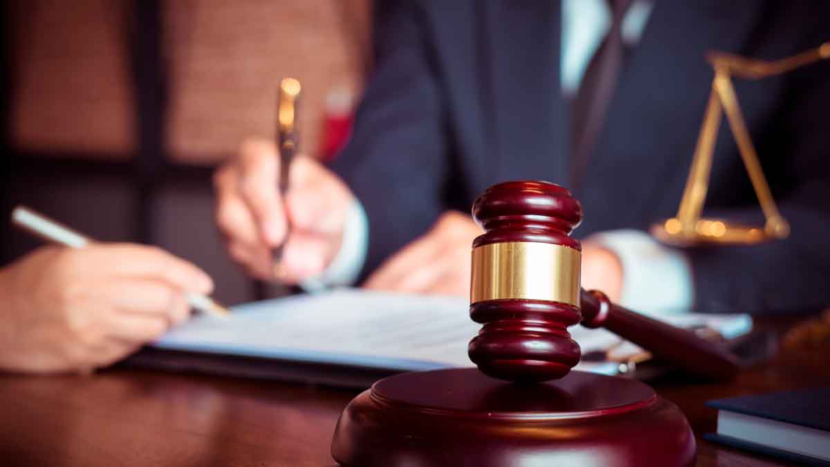 Mazo del juez sobre una mesa mientras un letrado firma la sentencia que otorga incapacidad absoluta y pensión de 2.000 € a una profesora