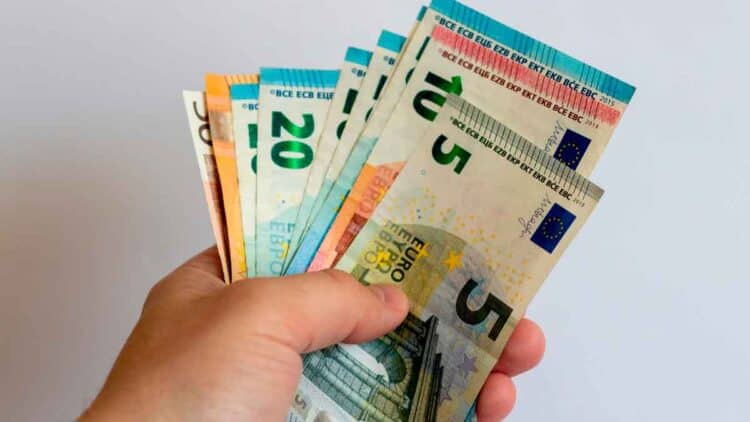 Mano sujetando varios billetes de euro, símbolo de transferencia de dinero entre familiares y posibles sanciones de Hacienda