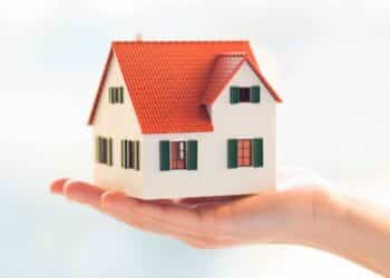 Maqueta de casa sostenida en la mano, símbolo de bienes privativos en matrimonio