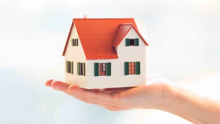 Maqueta de casa sostenida en la mano, símbolo de bienes privativos en matrimonio