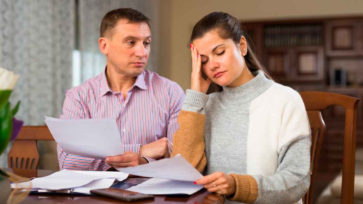 Pareja preocupada revisando papeles para hacer la declaración de la renta de un familiar fallecido en 2024