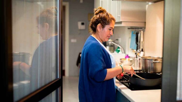 Mujer trabaja como empleada de hogar en la cocina, colectivo que podrá cobrar el subsidio SEPE para mayores de 52 años sin cotización completa