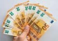 Mano sosteniendo abanico de billetes de 50 €, símbolo del microcrédito de 600 € del SEPE para formación laboral