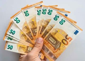 Mano sosteniendo abanico de billetes de 50 €, símbolo del microcrédito de 600 € del SEPE para formación laboral