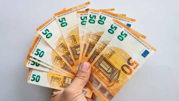 Mano sosteniendo abanico de billetes de 50 €, símbolo del microcrédito de 600 € del SEPE para formación laboral